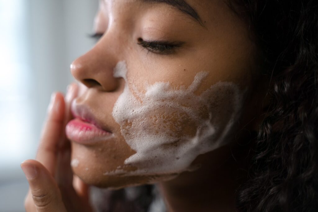A female is washing her face as part of how to repair the skin barrier steps
